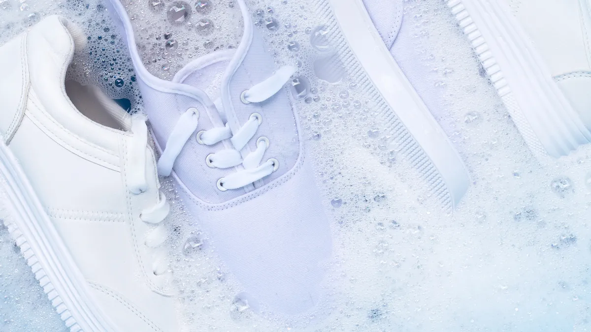 White canvas sneakers being washed in soapy water