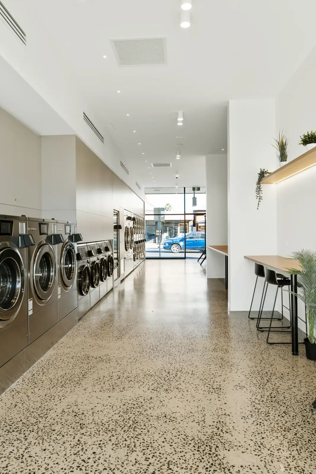 The bright, modern interior of Fresh Lab Laundromats in Maylands — a full row of Speed Queen washers, polished floors, work bench and seating